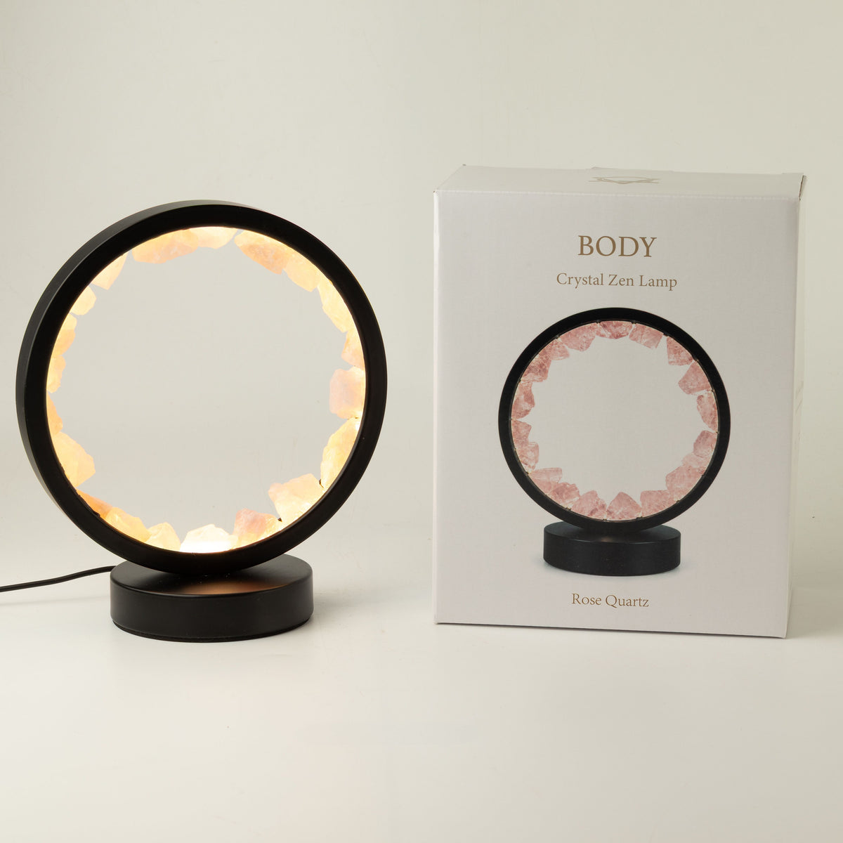 Illuminated rose quartz gemstone halo lamp on a black metal stand
